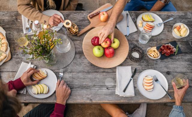 Picnic table with various South Tyrolean apples, apple juice, apple chips, and local products.