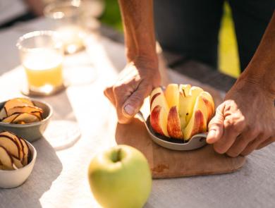 Freshly sliced apple, apple juice, and apple chips on a table.