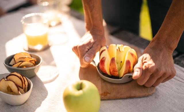 Freshly sliced apple, apple juice, and apple chips on a table.