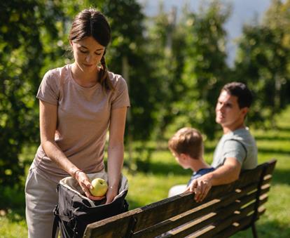 Family carries South Tyrolean apples in their backpack while walking.